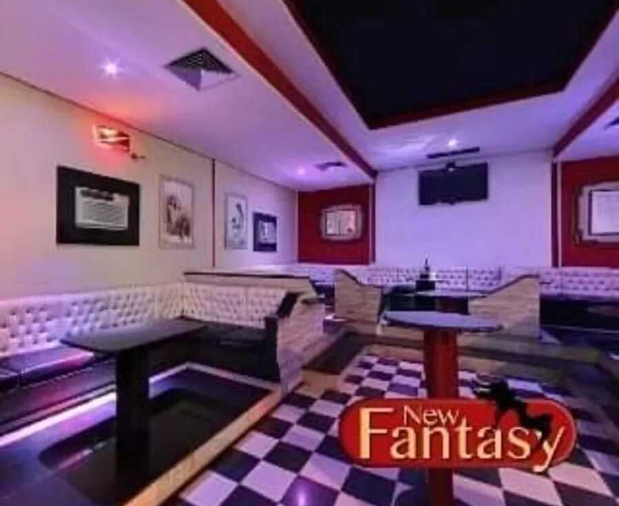 Salão interno da New Fantasy com sofás, mesas e iluminação aconchegante